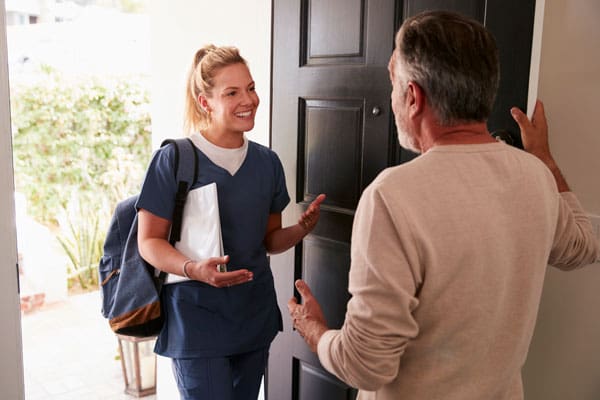 Caregiver at the front door greeting family member | TLC Your Way Hospice Care