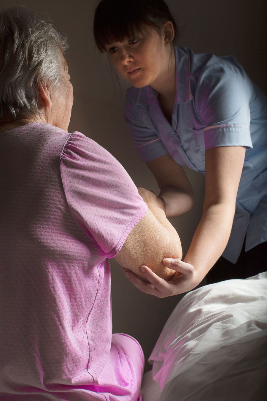 Caregiver assisting patient in and out of bed at home | TLC Your Way Hospice Care